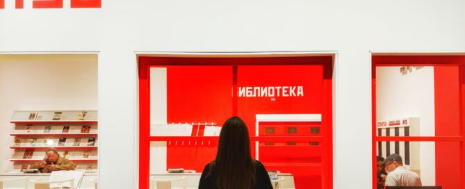 Woman looking at Russian Constructivist art at the Art Institute of Chicago. The art is white text and rectangles on a red background.