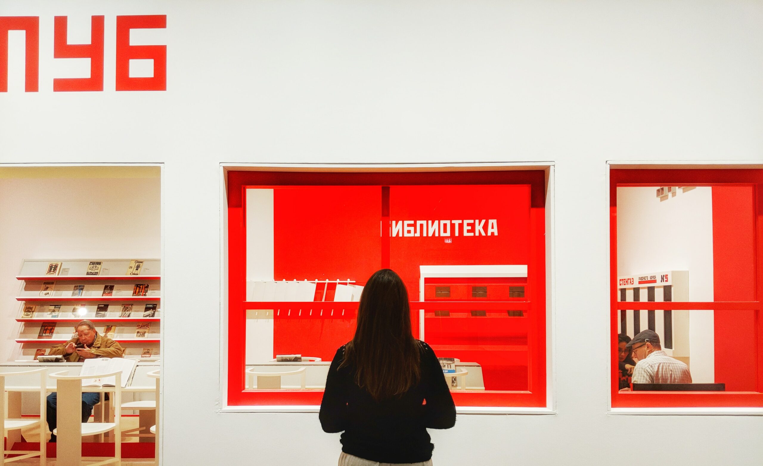 Woman looking at Russian Constructivist art at the Art Institute of Chicago. The art is white text and rectangles on a red background.