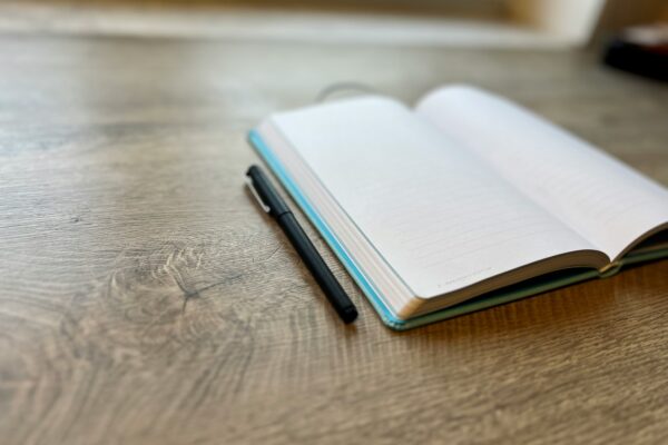 open journal with blank page and pen laying beside it