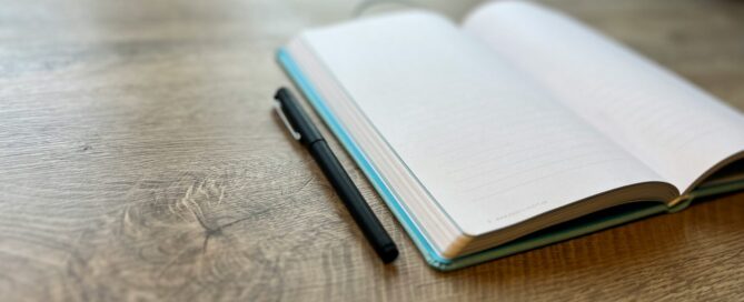 open journal with blank page and pen laying beside it