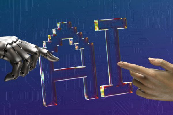 The letters "AI" with a human hand a robot hand pointing at it.